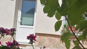 Un bâtiment avec une porte blanche, un mur en pierre et une fenêtre.