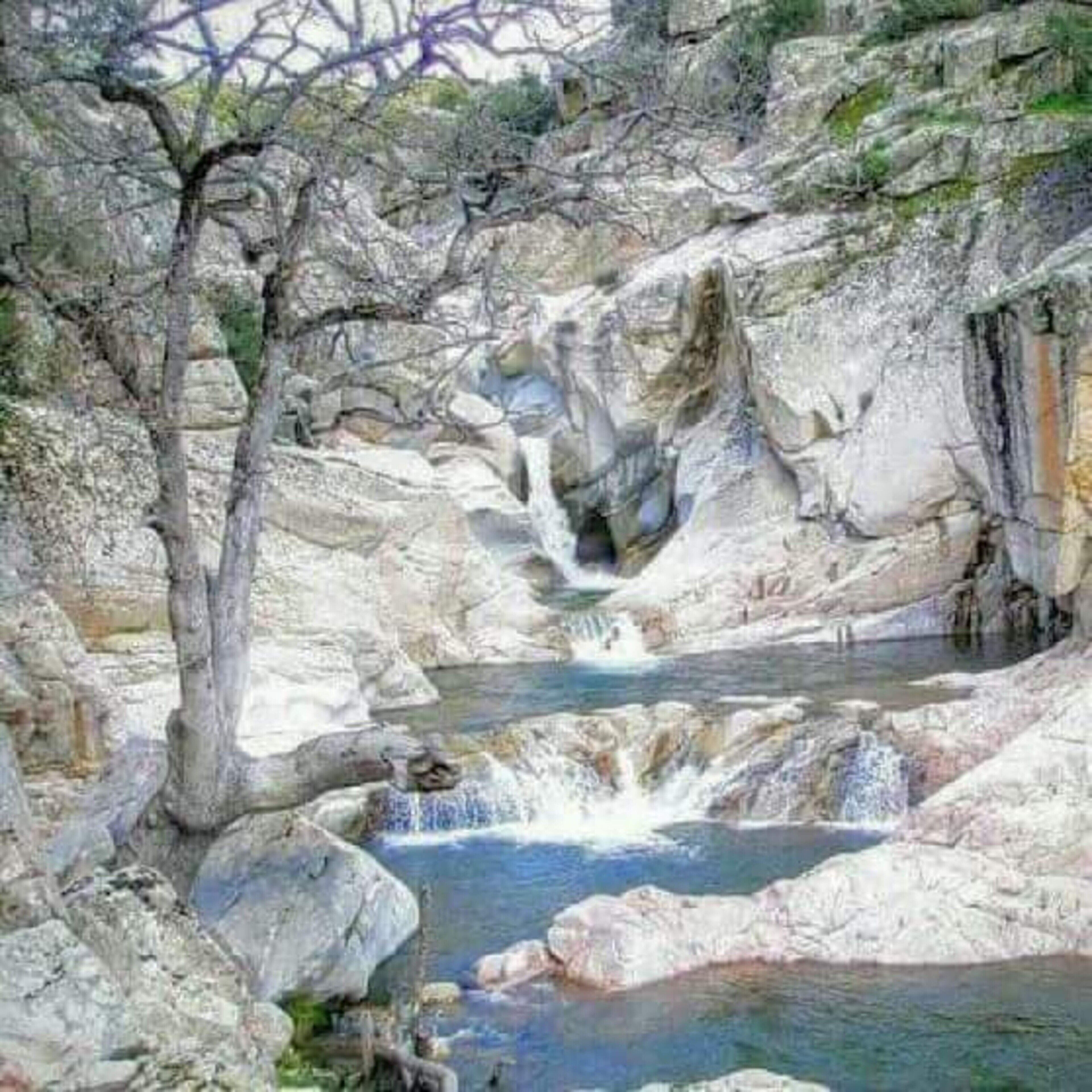 Paisaje rocoso natural con cascada y una poza.