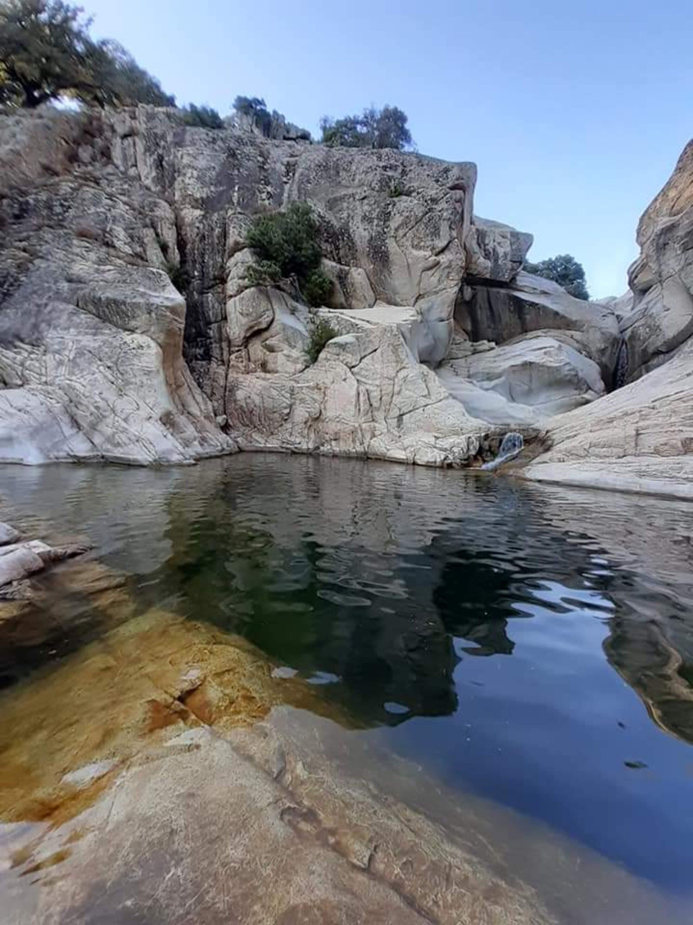 Un paisaje rocoso y natural con un cuerpo de agua transparente.