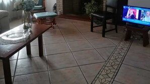 Un salon avec une cheminée, un téléviseur, un motif floral décorant le mur et un fauteuil.