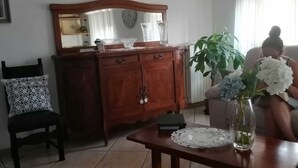 Un salon comprenant un meuble en bois, une chaise, une table avec un vase et un canapé.