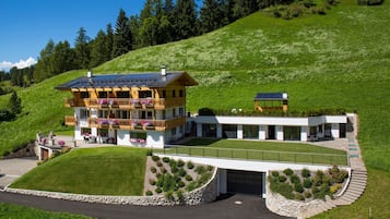 A two-story building with a balcony, a garage, and a well-maintained lawn.