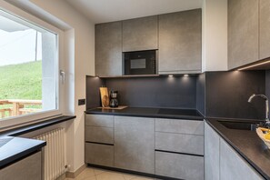 A modern kitchen with a built-in microwave, a coffee maker, and a window overlooking a grassy area.