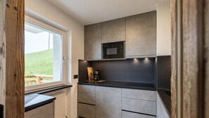 A modern kitchen with a built-in microwave, a window with a view of a grassy area, and a wooden door frame.