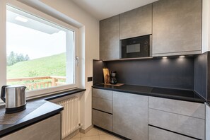 Eine moderne Küche mit Fenster, eingebauter Mikrowelle und Kaffeemaschine.
