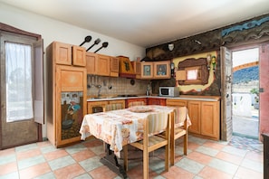 A kitchen with wooden cabinets, a dining table with a tablecloth, and a microwave.