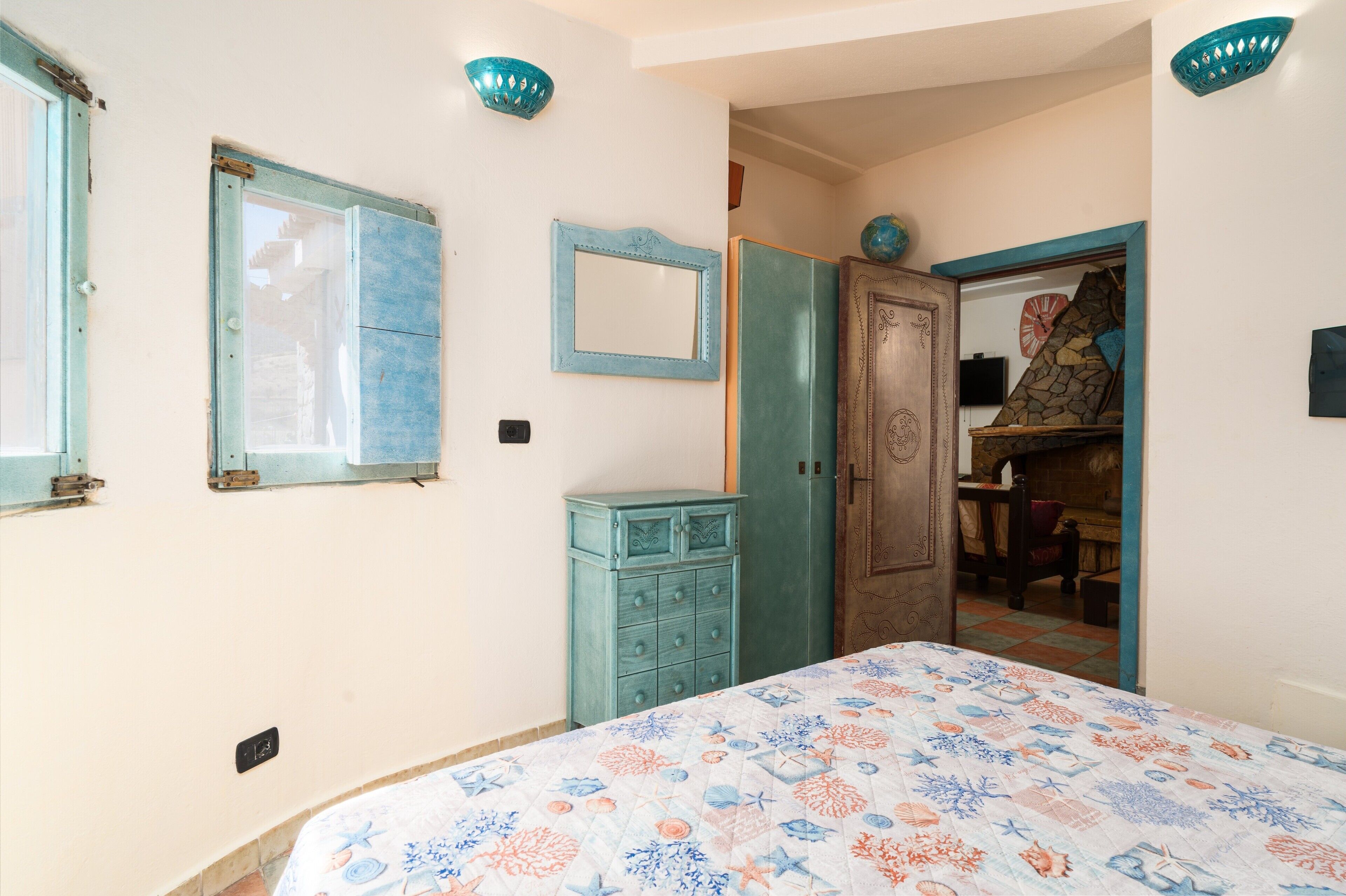 A bedroom with a bed, a dresser, a wardrobe, and a mirror.
