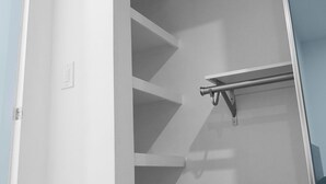 Un placard moderne et minimaliste, doté d’étagères intégrées et d’une poignée en métal.