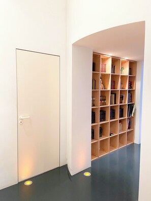 Un pasillo con una puerta cerrada y una estantería llena de libros.
