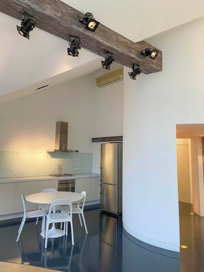 Una cocina moderna con una isla central, sillas blancas y un refrigerador de acero inoxidable.