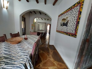 Uma área de refeições com toalha de mesa estampada em zebra, cadeiras de madeira e um cesto trançado.