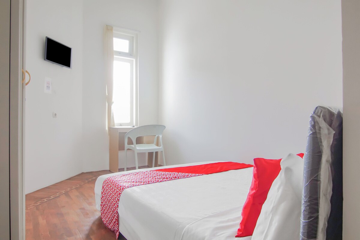 Una habitación con cama, sillón, televisión y ventana.