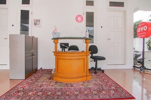 Une pièce comprenant un grand meuble orange, un tapis à motifs, un bureau avec une chaise et un panneau indiquant une mesure de sécurité liée à la COVID-19.