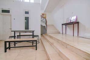 Una escalera que lleva a un segundo piso, con una mesa y sillas al frente.