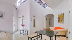 Amplia sala de estar con techo alto, mesa de comedor, sofá y una escalera que conduce a un nivel superior.