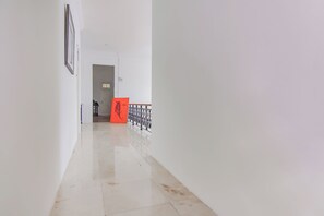 Een gang met een gepolijste vloer, een deur aan het einde en een balustrade met een decoratief ontwerp.