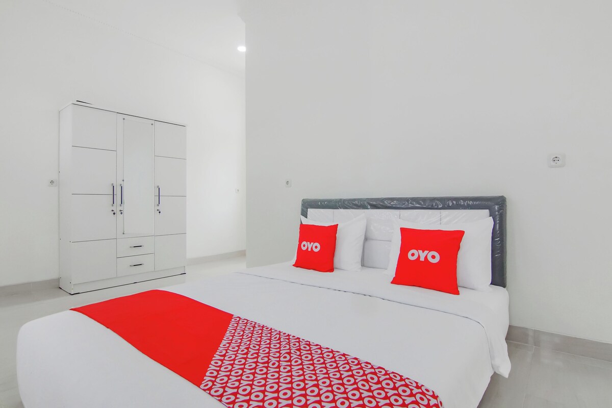 Une chambre d’hôtel avec un lit, une armoire et une couverture à motifs rouges et blancs.