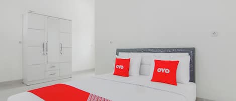 A hotel room with a bed, a wardrobe, and a bedside table.