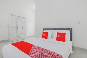 Une chambre d’hôtel avec un lit, une armoire et une couverture à motifs rouges et blancs.