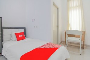 Una habitación de hotel con una cama, una silla, una puerta y una ventana con cortinas.