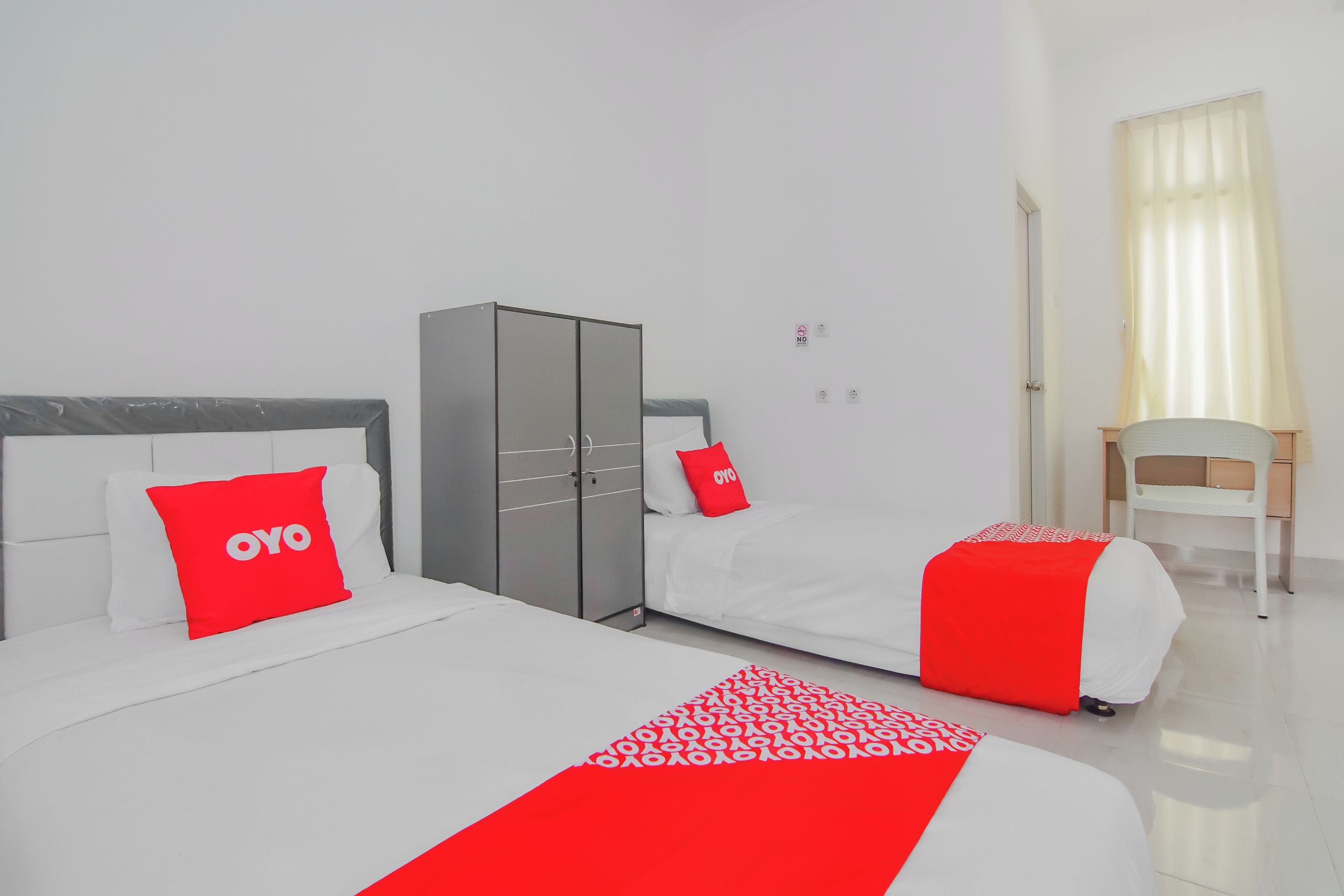 A hotel room with a large bed, a wardrobe, a desk, and a chair.