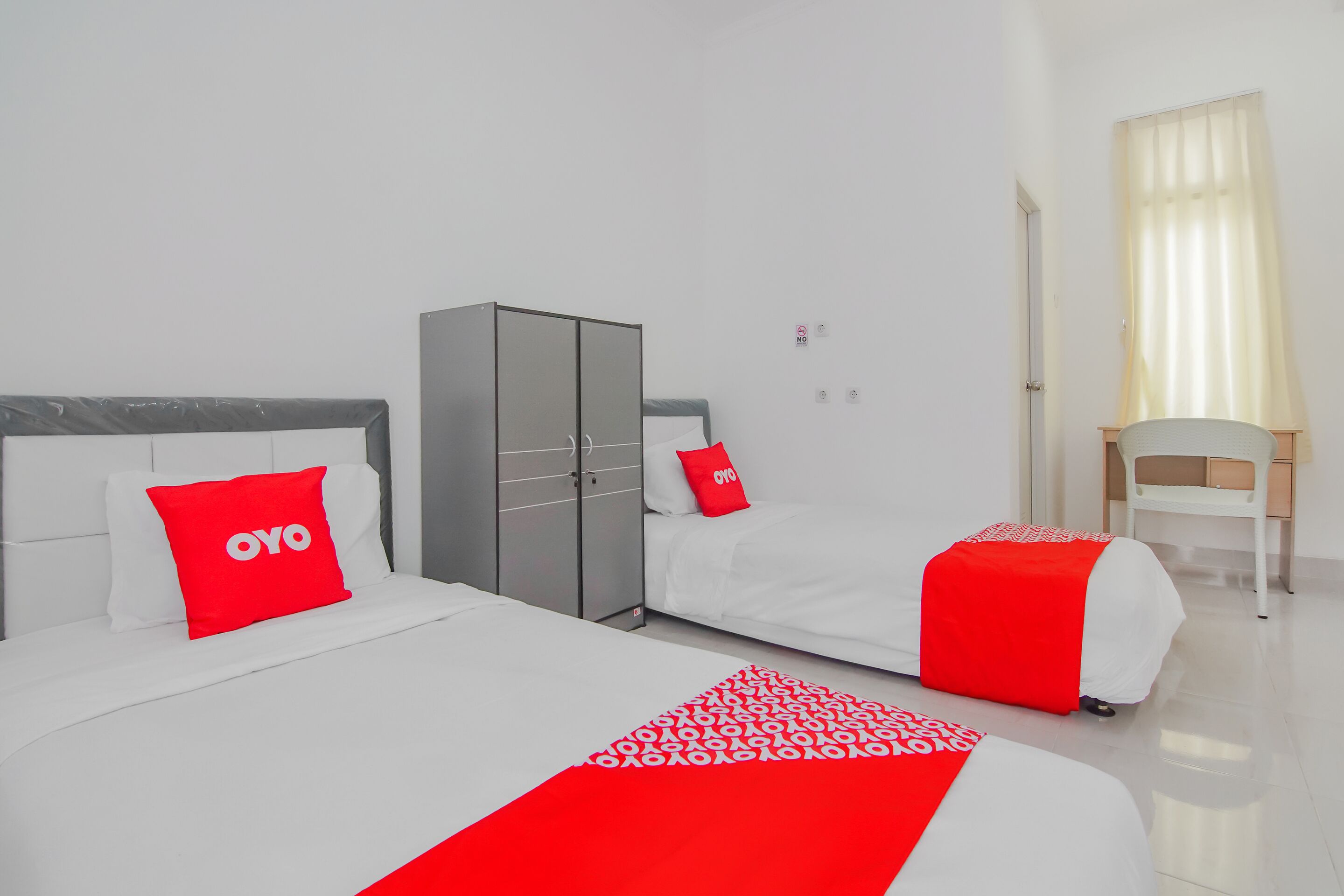 Een hotelkamer met een bed, een kledingkast, een bureau en een stoel.