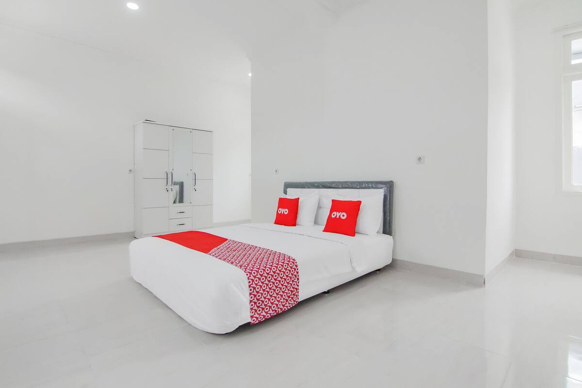 Une chambre à coucher moderne avec un lit, une armoire blanche et une fenêtre.