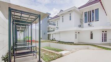 A residential building with a covered outdoor seating area, a small garden, and a tiled pool.