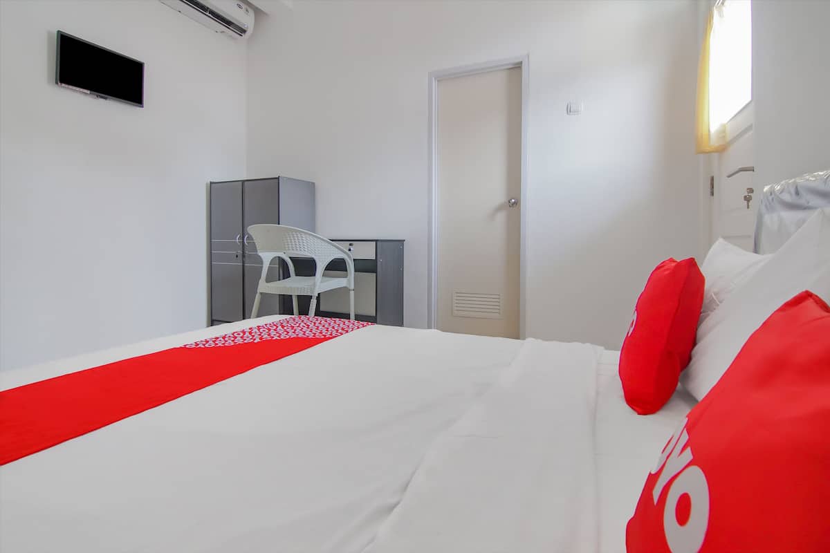 Une chambre d’hôtel avec un lit, un bureau, une chaise et une armoire.