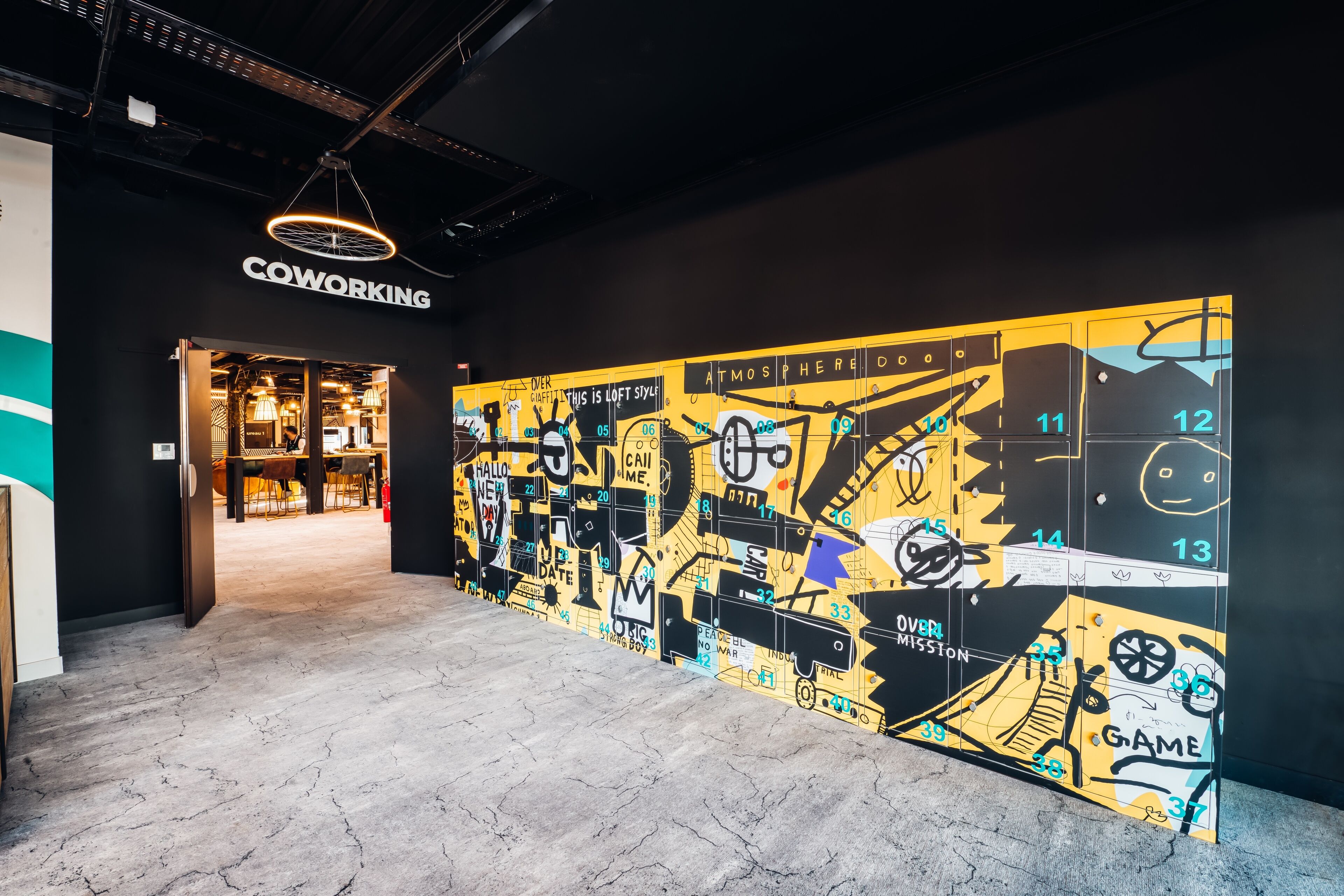 A coworking space with a large, colorful mural on the wall and a sign that reads "Coworking".