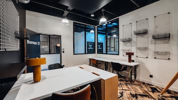 A modern office space with a white table, black chairs, and a unique yellow lamp.