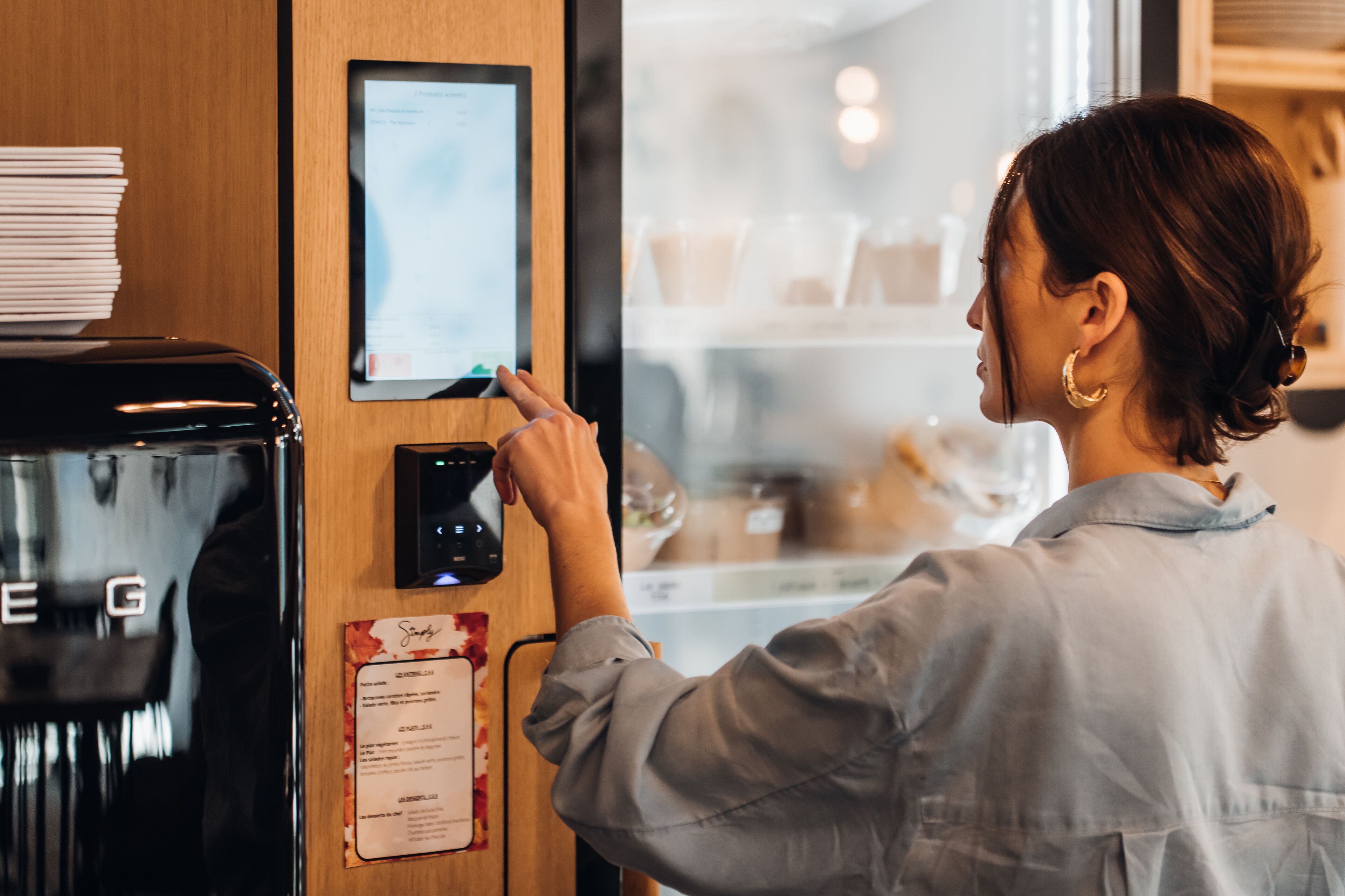 Una persona interactuando con un quiosco digital en una cafetería.