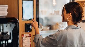 Una persona interactuando con un quiosco digital en una cafetería.