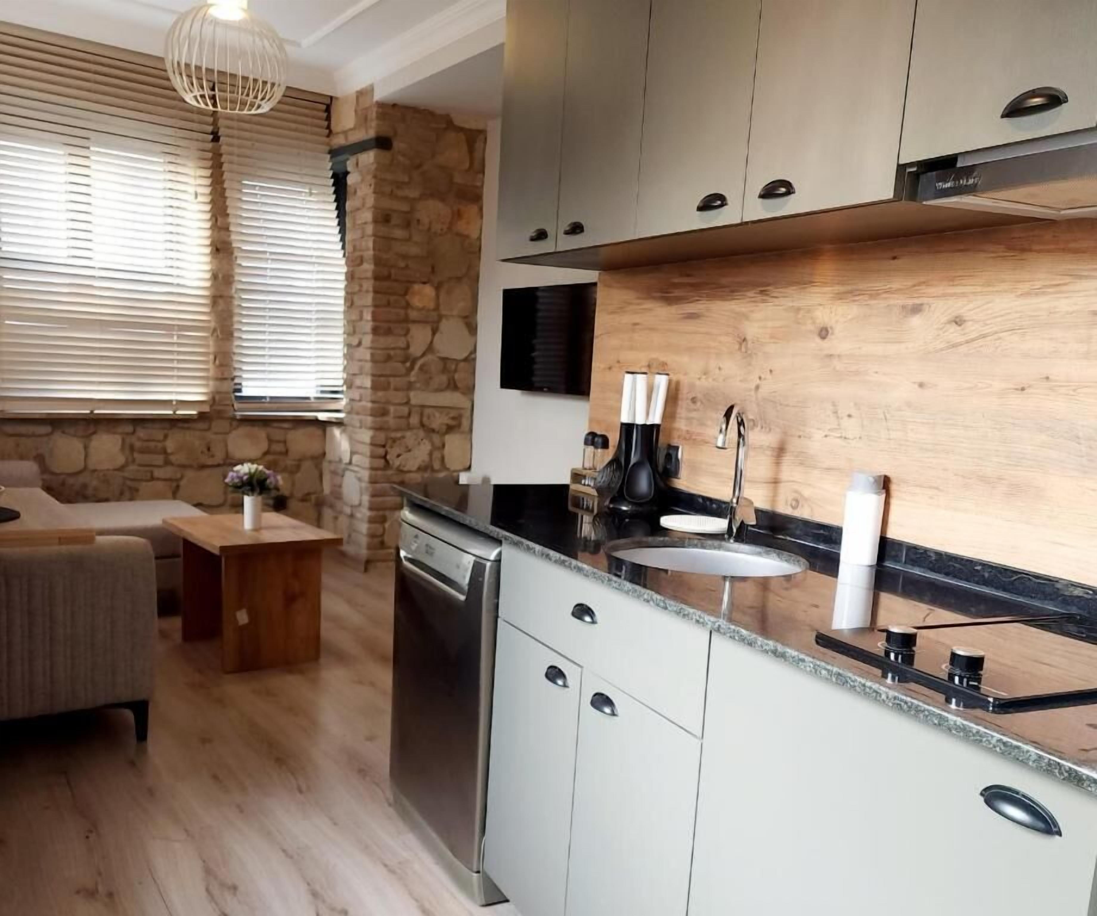 Una cucina moderna con una parete a tema in pietra, una lavastoviglie integrata e un piano di lavoro in legno.