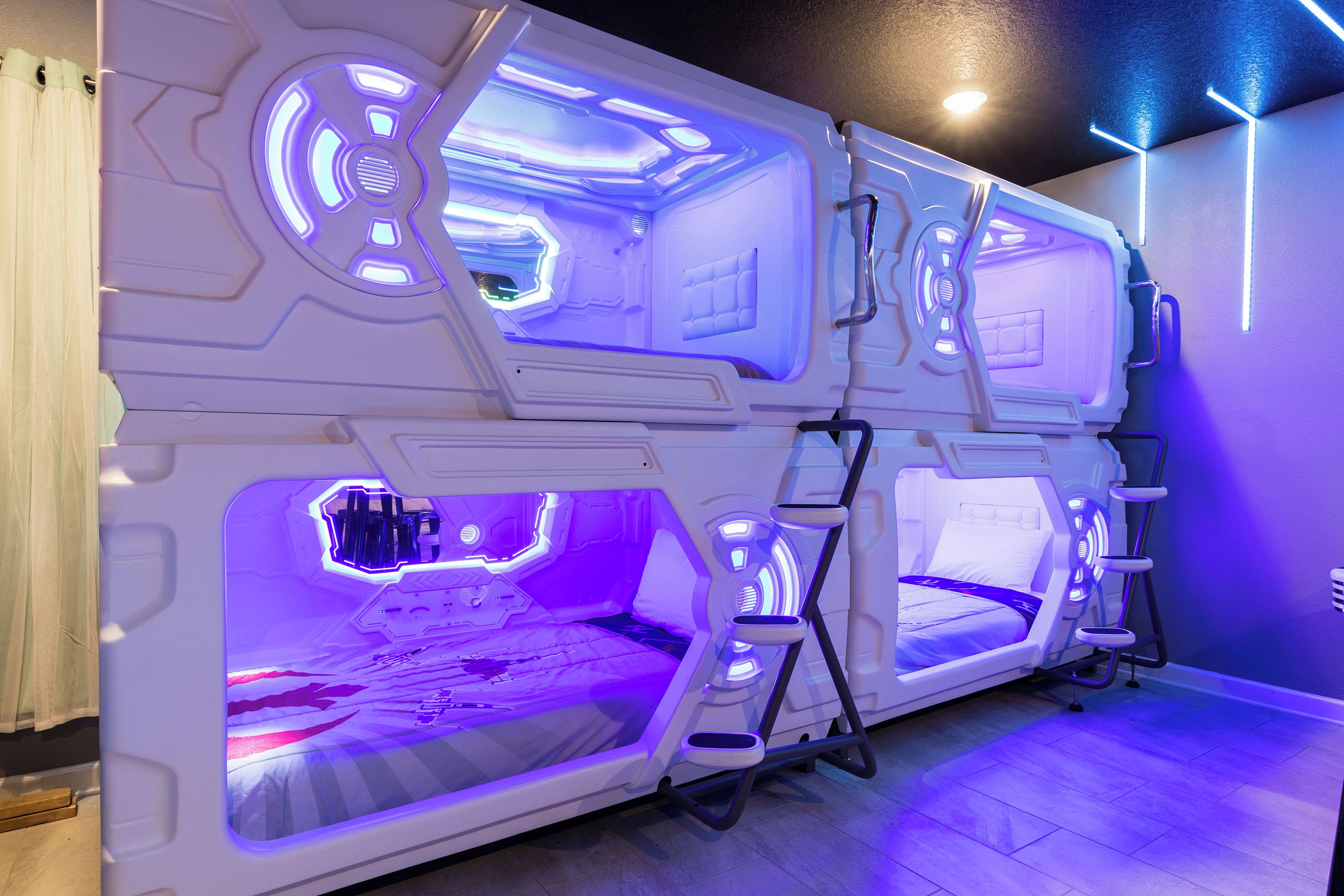 A futuristic room with a central bed, two smaller beds, and a seating area.