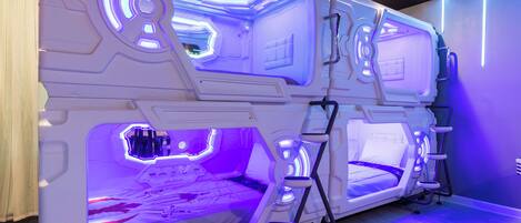 A futuristic room with a central bed, two smaller beds, and a seating area.
