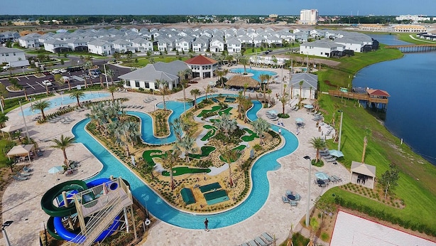 An aerial view of a resort with multiple swimming pools, a water slide, and a golf course. - Lakeview Luxury Villa with Everything! (Kissimmee)