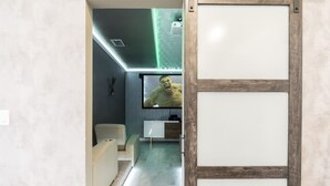 A modern interior with a minimalist design, featuring a white sofa, a wooden-framed sliding door, and a flat-screen TV displaying a character. - Lakeview Luxury Villa with Everything! (Kissimmee)