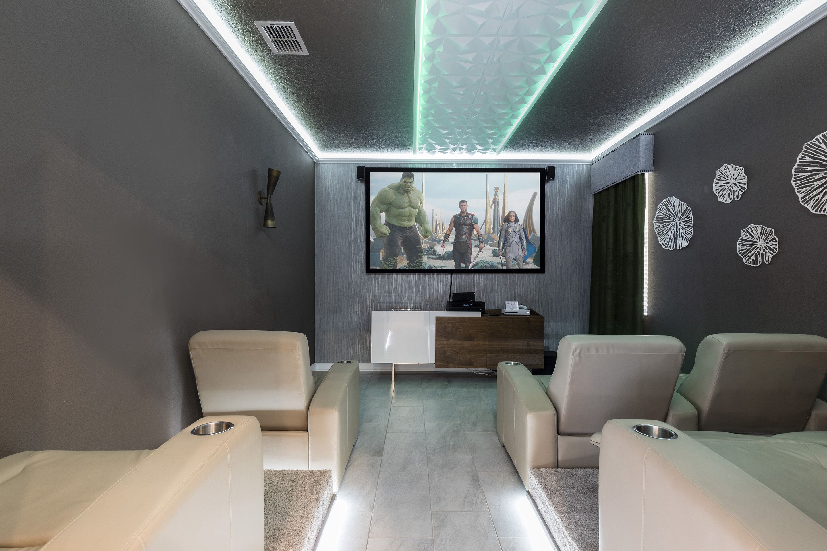 A modern home theater with a flat-screen TV, reclining chairs, and a wooden entertainment unit.