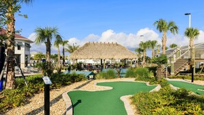 A miniature golf course with a thatched-roof building in the background, surrounded by palm trees and greenery. - Lakeview Luxury Villa with Everything! (Kissimmee)