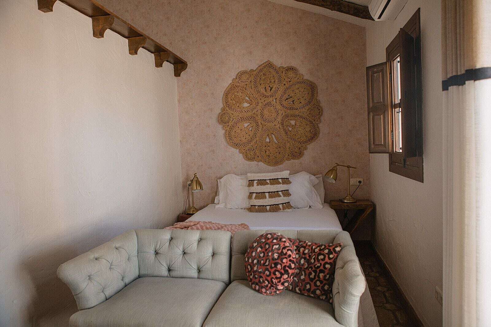 Un dormitorio con cama, un adorno de pared, una mesita de noche y una silla.