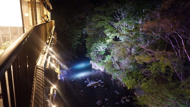 A night view of a building with a balcony overlooking a rocky stream and dense foliage. - Livemax Resort Amagi Yugashima (Izu)