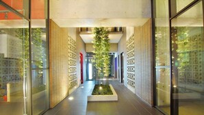 Un pasillo moderno con paredes de vidrio, un jardín vertical central y baldosas de pared con diseño.