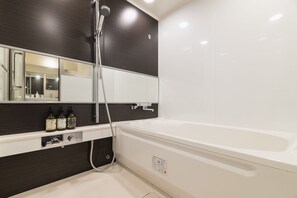 A modern bathroom with a bathtub, a shower, a large mirror, and two bottles of shampoo on the vanity. - Hotel The Hakata Terrace Fukuoka (Fukuoka)