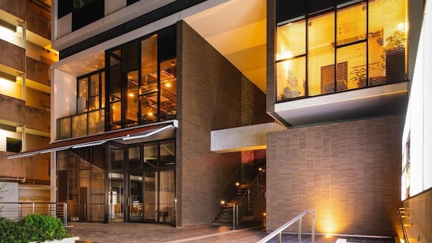 Un edificio moderno con entrada de vidrio, una escalera y fachada de ladrillo.