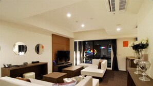 Una sala de estar moderna con televisor, sofás, una mesa de centro y un escritorio con computadora.