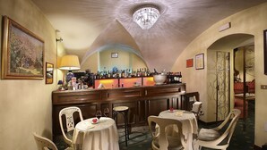 A bar area with a counter, chairs, and a chandelier.
