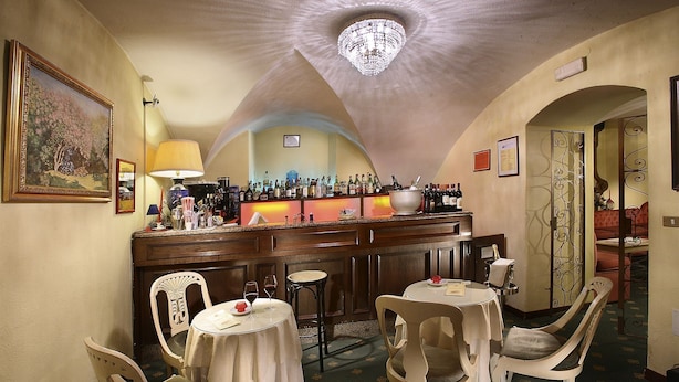 Eine Bar mit Tresen, Stühlen und einem Chandelier.