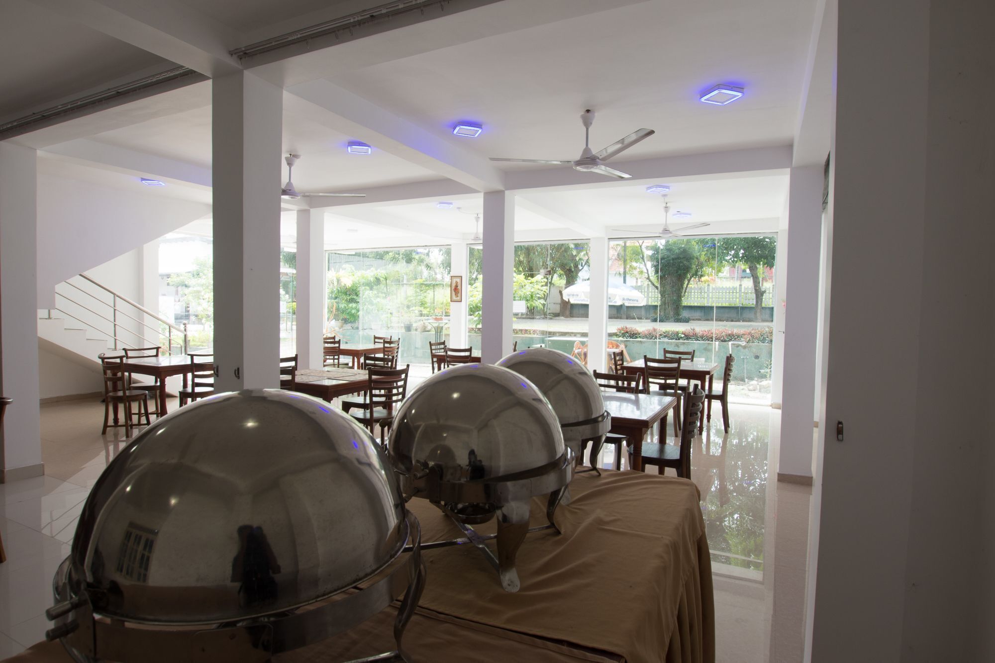 A restaurant with a modern interior, large windows, and a pool view.