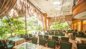 A restaurant with tables and chairs arranged indoors, large windows with curtains, and a view of greenery outside. - Cheng Pao Hotel (Puli)